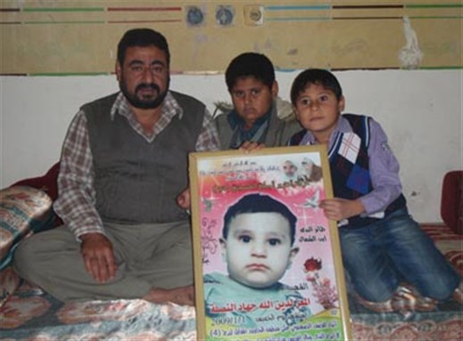 [Jihad, Mu`tassam, and Zeid Nasla with a picture of M`uz Nasla, killed during the attack. Image from pchrgaza.org.]