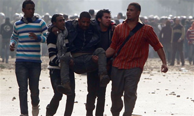[Protesters assist an injured fellow protester during clashes with army soldiers at the cabinet near Tahrir Square in Cairo 16 December 2011. Image from Reuters]