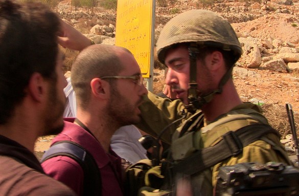[A demonstrator and Israeli soldier stare at each other during a protest against settler violence and the Israeli occupation in Occupied Palestine: taken by Scott Campbell, uploaded via Flickr]