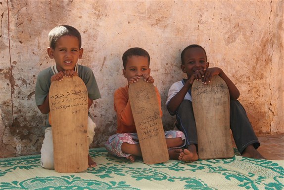 Young boys taking Qur'an lessons from wooden tablets in Mauritania, West Africa (via Wikimedia Commons)
