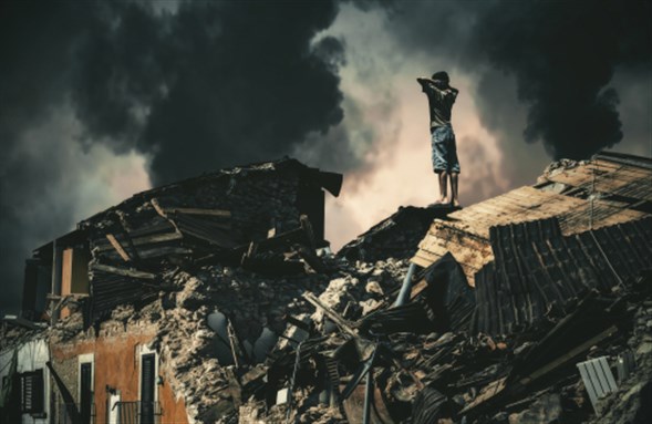 Homeless little boy watching destroyed houses and bombarded city.  By Meysam Azarneshin via Shutterstock.