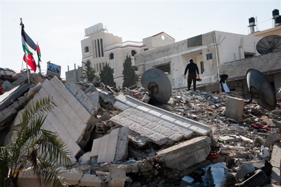 A man combs amid the rubble of the Palestinian National Authority Council of Ministers building in Gaza, December 3, 2012. Image via Shutterstock.