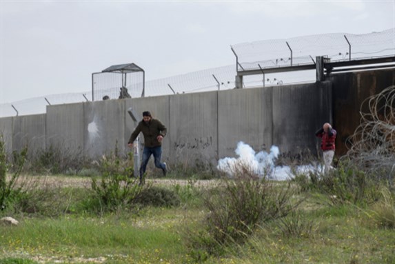 A protester runs away from the wall after the Israeli soldiers throw tear gas grenades in Bilin, West Bank, Palestine, 15/02/19.  Image via Shutterstock.