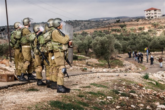 31 December 2010: Israeli Defense Force squad faces protesters during weekly demonstrations against Palestinian land confiscation and the building of Jewish settlement in Bilin. Image via Shutterstock.