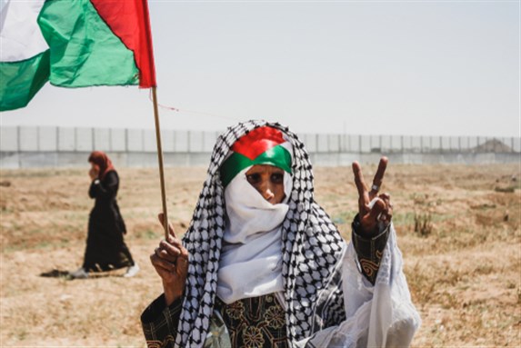Older woman holds Palestinian flag during the 