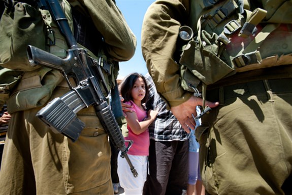 A Palestinian girl faces Israeli soldiers in a protest against the Israeli separation wall in Al-Walaja, West Bank, in Occupied Palestinian Territories on 27 August 2011. Image via Shutterstock.