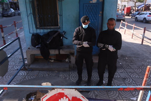 Two policemen pray on Al-Rimal St (central Gaza Strip) while taking preventative measures against COVID-19 upon the announcement of the emergence of two cases of Gazan men infected with the virus (22 March 2020). Photo by Samar Abu Elouf.