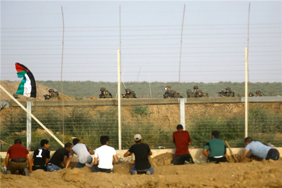 Palestinian protesters try to cut the border fence east of Gaza City, under the watch of Israeli forces, during a demonstration on 25 May 2018. Image by Alan Taylor.