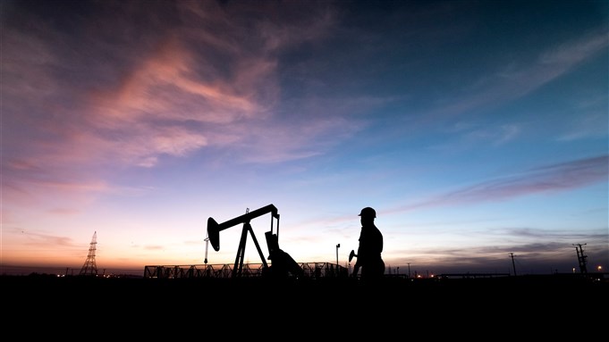 Silhouette of oilfield worker at crude oil pump in the oilfield at sunset. from Shutterstock