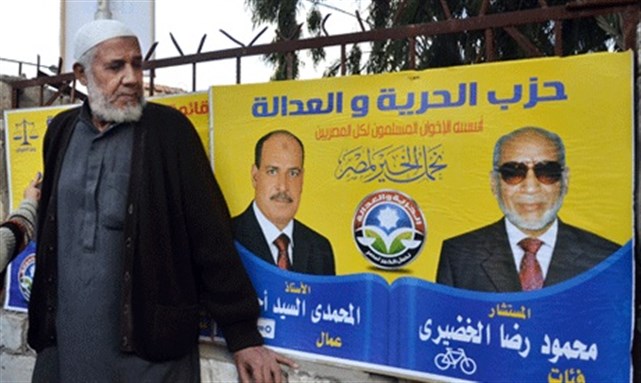 [An Egyptian man looks at a campaign banner in Arabic that reads, \"The Freedom and Justice party,\" on the second day of parliamentary elections in Alexandria. Image from AP]