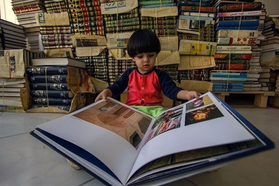 Child reading book in Qom. Image via Wikimedia Commons.