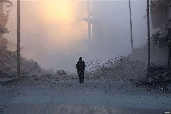 [Image of a man on his bicycle in what is left of his neighborhood in Aleppo. Image by Don Johnston via Flickr]