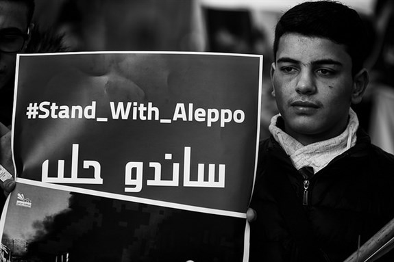 [Image of a man standing in solidarity with the people of Aleppo, taken in Berlin, Germany. Image by Thorsten Strasas via Flickr]