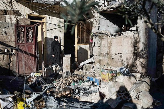 [Feb. 9, 2012. A Syrian woman stands among the rubble of her house, destroyed by a Syrian Army mortar, in al-Qsair. Image by Freeedom House.]