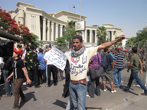 [A protester outside the Supreme Constitutional Court holding a sign that says \" \"No to Shafiq and to the Muslim Brotherhood and down with military rule too.\" Image originally posted to Flickr by Wessam Deweny.