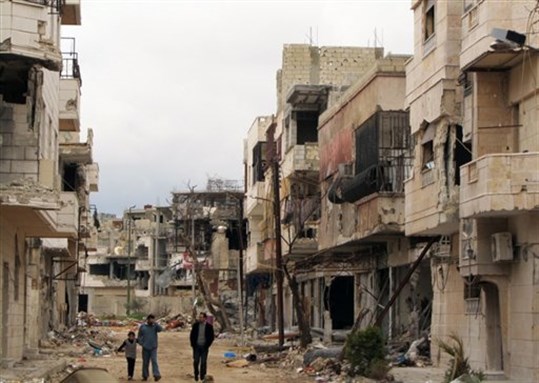(Syrians walk between destroyed buildings in the Inshaat neighborhood of Homs, Syria, April 15, 2012. Image by Anonymous/AP Photo.)