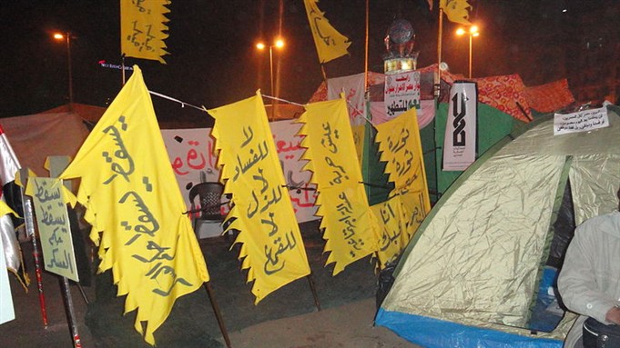 [Anti-SCAF, anti-military trials signs in Tahrir Square. From Wikimedia Commons. Image by Osama Khalid.]