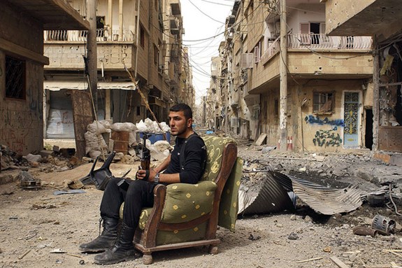 [Image of a member of the Free Syrian Army sits in a debris-strewn street in Deir al-Zor, Syria. Image by Jordi Bernabeu Farrus via Flickr]