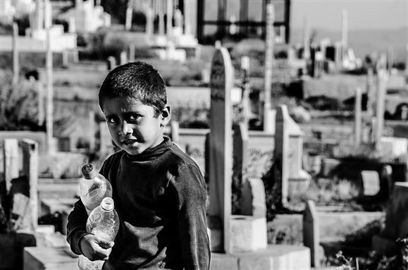 [Child living in a cemetary that his father guards. Rukn ElDeen, Damascus. Photo by Ehab Al-Jabi.]