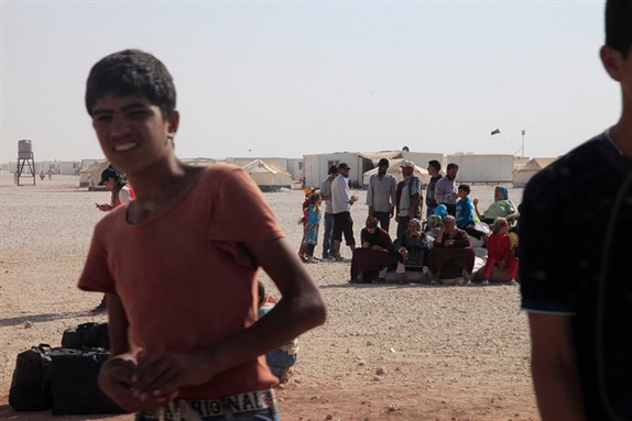 [Refugees from Syria in the Zaatari camp wait for buses at the edge of the camp to take them to other destinations in Jordan. Image from UK Department of International Development / Flickr]
