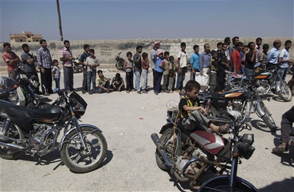 [Syrians line up to wait their turn to buy bread in the town of Azaz on the outskirts of Aleppo, Syria, August 15, 2012. Image by Khalil Hamra/AP Photo.]