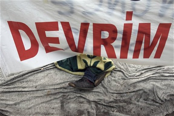 [A protester sleeps under a banner that reads ``Revolution`` at the Gezi Park in Istanbul, Turkey, 12 June 2013. AP Photo/Thanassis Stavrakis]