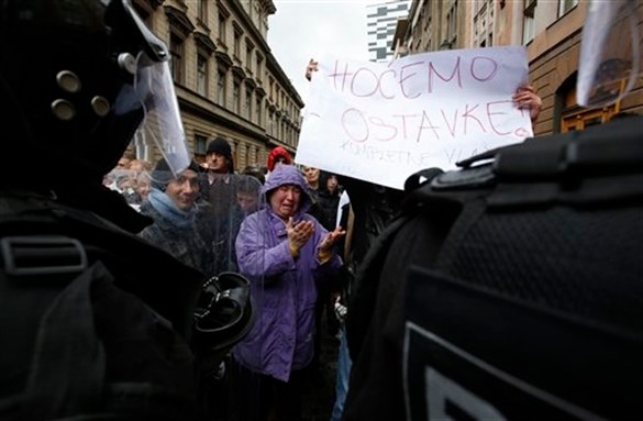 [A woman protests in front of a police cordon with banner “We want resignations” in the Bosnian capital of Sarajevo on Sunday 9 February 2014. Image by Amel Emric via Associated Press]
