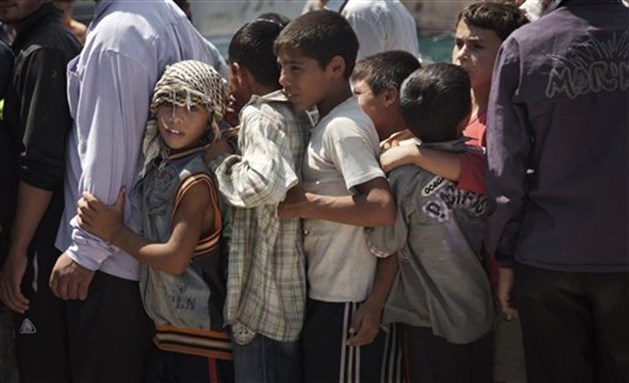 [Syrian children line up to wait their turn to buy bread in the town of Azaz on the outskirts of Aleppo, Syria, Aug. 15, 2012. Image by Khalil Hamra/AP Photo.]