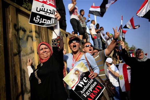 [Opponents of Egypt`s Islamist President Mohammed Morsi chant slogans during a protest outside the presidential palace, in Cairo, Egypt, 3 July, 2013. The poster with partial translation of Arabic reads, \"we support the Egyptian military.\" AP Photo/Khalil Hamra]
