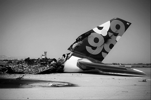 [A destroyed aircraft from a NATO strike in the Tripoli International Airport. Image by Il Fatto Quotidiano/Flickr.]
