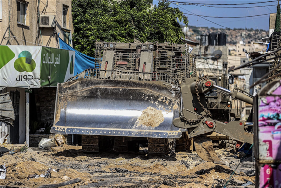 AN ISRAELI MILITARY BULLDOZER SEEN LEVELING ROADS AND DESTROYING THE CENTER OF THE JENIN REFUGEE CAMP DURING A RAID ON THE CAMP NEAR THE WEST BANK CITY OF JENIN, JULY 3, 2023. (PHOTO: NASSER ISHTAYEH/SOPA IMAGES VIA ZUMA PRESS WIRE/APA IMAGES)