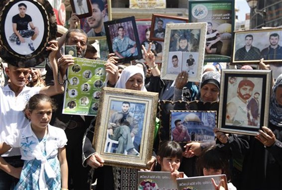[Palestinians hold photographs of their relatives jailed in Israel during a support rally for Palestinian prisoners on hunger strike, in the West Bank city of Ramallah, May 5, 2012. Image by Majdi Mohammed/AP Photo.]