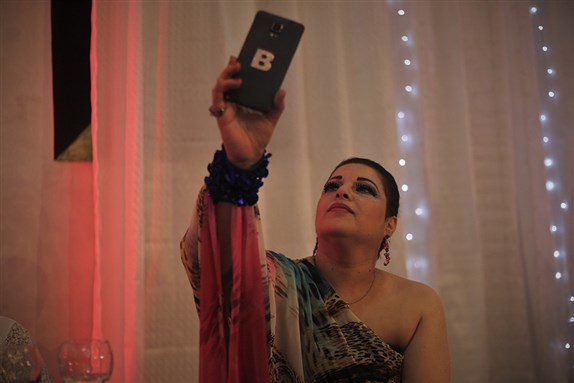 [Mom takes a selfie at their Christian friends’ wedding in Gaza City. Her mobile is marked with the first letter of her name, Beesan. Photo by Lara Aburamadan]