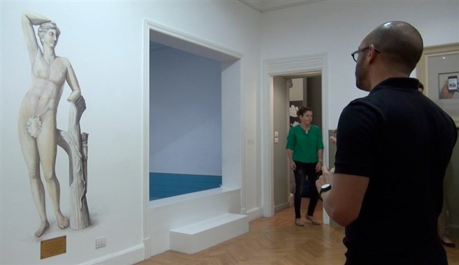 [Alexandrian artist Mahmoud Khaled gives visitors a tour of his exhibition. Image courtesy of MedrarTV.]