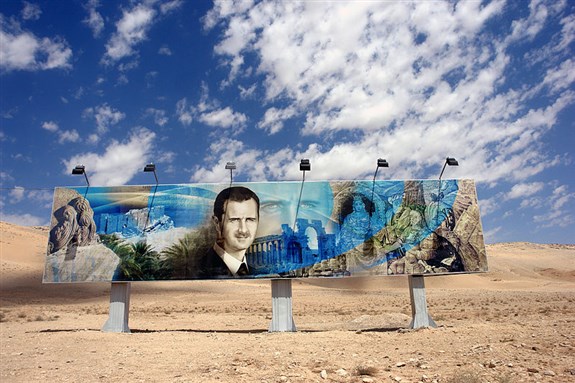 [Roadside mural of Bashar al-Assad along the Damascus-Aleppo highway. Image from Wikimedia Commons]