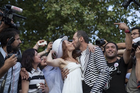 [Newly wed couple, Nuray Çokol and Ozgur Kaya, come into the park to meet with the guests who gathered for the ceremony. Riot police denied access to Gezi Park ahead of the wedding ceremony of Nuray and Ozgur, who met during the first wave of Gezi protests. The couple had invited all protesters to their wedding at Gezi Park. © Saner Sen / NarPhotos.]