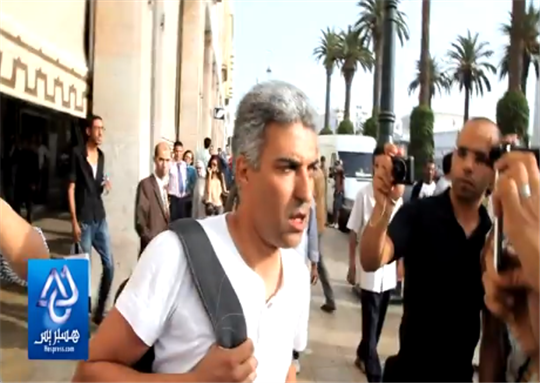 [Omar Brouksy displays the injuries he sustained after police beat and harassed him. Image from Youtube video.]
