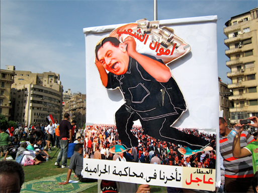 [20 May 2011, protesters demanding the prosecution of Hosni Mubarak. The caricature shows Mubarak carrying on his back a bag of \"the people`s money\". The bottom in Arabic reads:\"BREAKING: We are delaying the prosecution of thieves\". Image originally posted to Flickr by Gigi Ibrahim]