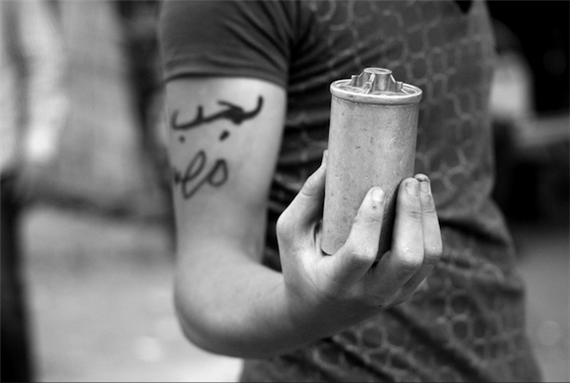[28 June 2011, a protester holding tear gas canister the Arabic on his arm reads:\"I love Egypt\". Image originally posted to Flickr by lilian Wagdy]