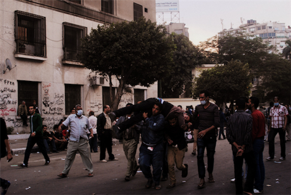 [27 November 2012, protesters carrying an injured man following clashes with the security forces, Egypt. Image originally posted to Flickr by Lilian Wagdy]