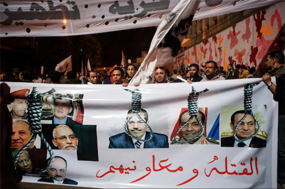 [19 November 2013, on Mohamed Mohamoud Street, protesters gather to demonstrate against Ministry of Interior and repeat demands of January 25 Revolution. The banner showing pictures of former presidents and officials reads: \"Killers and their accomplices\". Image originally posted to Flickr by Hossam el-Hamalawy] 