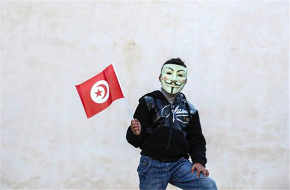 [A civilian wearing a mask holds a Tunisian flag in Sidi Bouzid, central Tunisia. Tunisia adopted a new constitution this week, receiving accolades from the international community. Photo courtesy of the Associated Press.]
