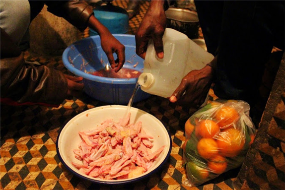 [Collective meal in an Ivorian ghetto (overcrowded and derelict collective housing arrangement for migrants) nicknamed \"Le Consulat.\" Image by Sébastien Bachelet.]