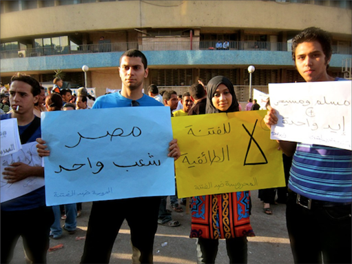 [13 May 2011, anti-sectarianism protest calling for Egyptian unity. The poster on the right in Arabic reads: \"Muslims and Christians are one hand.\" Photo by Gigi Ibrahim via Flickr.]