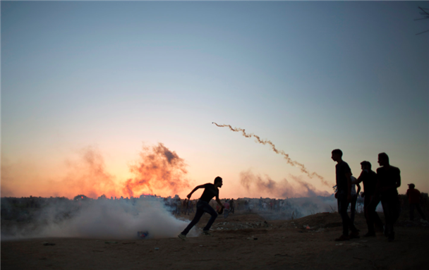[Palestinian demonstrators run for cover from tear gas fired by Israeli soldiers during clashes on the Israeli border with Gaza in Bureij, central Gaza Strip, Thursday, October 15, 2015. (AP Photo / Khalil Hamra)]