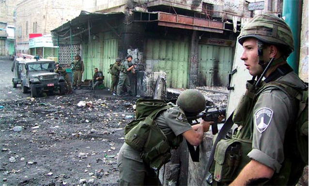 [Israeli Defense Forces fight with young Palestinians in West Bank town of Hebron, November 2000. Photo by Devin Asch and uploaded via Wikipedia]