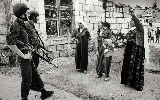 [Confrontation–Jabalia Camp, Gaza Strip, Palestine The women are complaining about the arrest and mistreatment of Palestinian youths. It became official policy, during this period, for the occupying forces to break the bones of any youth caught throwing stones at military personnel. Shortly after this shot was taken the women were dispersed using baton charges and tear gas. Jabalia, Gaza Strip–1988. Photo by Robert Croma and uploaded via Flickr]