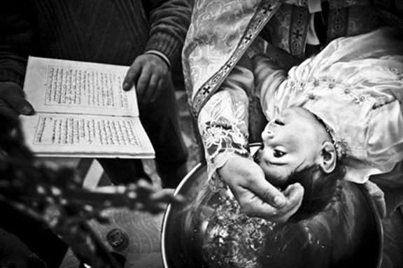 [A child is baptized in al Tahira church in Qaraqosh. Photo by Andy Spyra.]