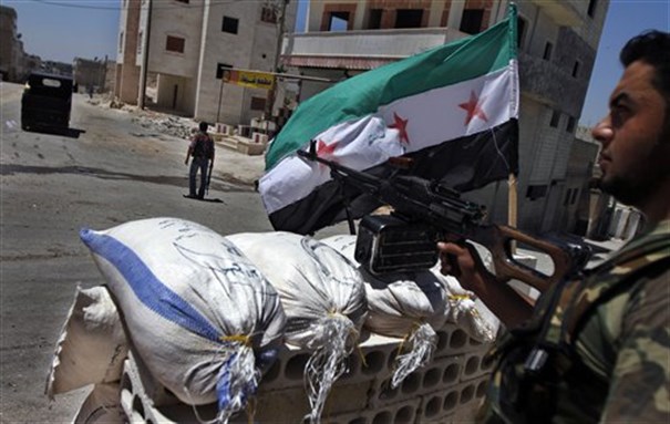 [ A Free Syrian Army solider aims his weapon at a checkpoint in the northern town of Ariha, on the outskirts of Idlib, Syria, June 10, 2012. Image by Khalil Hamra/AP Photo.]