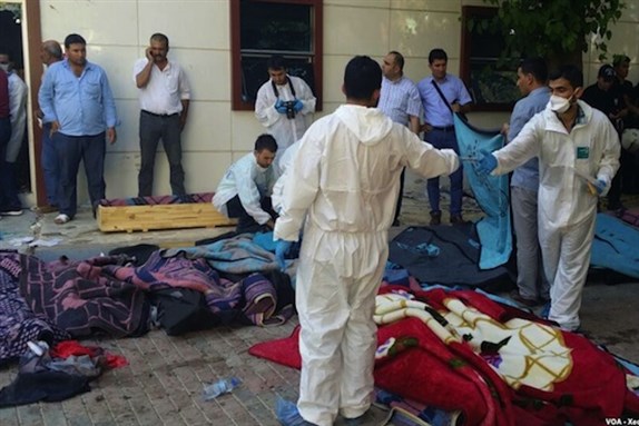 [Forensic experts examine the scene of the Suruç bombing, 21 July 2015, Suruç, Sanliurfa, Turkey. Image via Wikimedia Commons.]